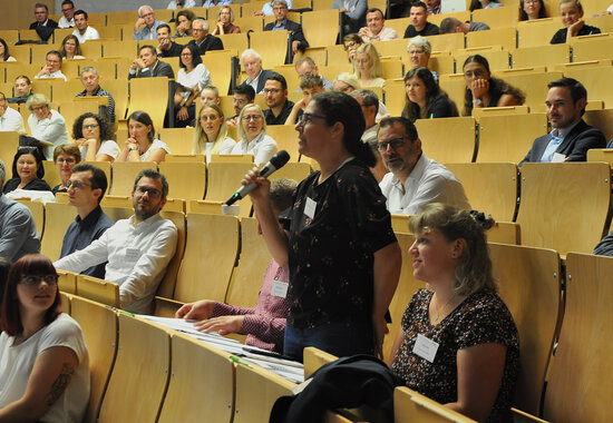 Eine Teilnehmerin stellt eine Frage im Plenum